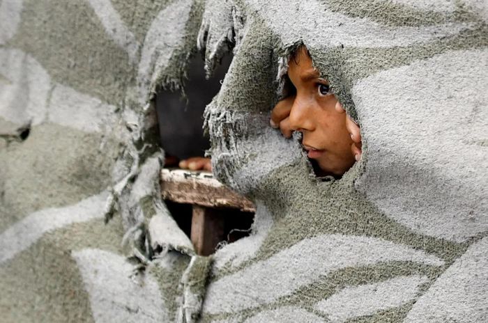  Một em nhỏ Palestine đứng nhìn lễ tang bé trai 3 tuổi Saadi Ghalia, nạn nhân thiệt mạng trong một vụ pháo kích bằng đạn xe tăng của Israel, tại Deir al-Balah, Dải Gaza. Theo Văn phòng điều phối các vấn đề nhân đạo của Liên hợp quốc (OCHA), từ ngày 2-9/9, ít nhất 35 người Palestine được báo cáo thiệt mạng và 104 người bị thương tại Gaza. Tính từ khi lệnh ngừng bắn được công bố ngày 10/10/2025, số người Palestine thiệt mạng do phía Gaza báo cáo đã lên tới 1.358 người và 4.541 người bị thương. Trong khi đó, phần lớn trong số khoảng 2,1 triệu người dân Gaza vẫn phải sống trong các khu vực tạm cư chật chội và đối mặt với tình trạng thiếu thốn các dịch vụ thiết yếu. OCHA cho biết, 91% số hộ gia đình tại Gaza đang phải đối mặt với tình trạng mất an ninh nguồn nước từ mức trung bình đến cao, trong khi hệ thống y tế và vệ sinh tiếp tục chịu sức ép lớn. Trước đó, UNICEF thông báo, ít nhất 300 trẻ em đã bị báo cáo thiệt mạng tại Gaza trong 300 ngày, tương đương trung bình một trẻ em thiệt mạng mỗi ngày. Những con số ấy khiến hình ảnh một đứa trẻ đứng trước lễ tang của một đứa trẻ khác trở nên đặc biệt ám ảnh, khi tuổi thơ của hàng triệu em nhỏ Gaza tiếp tục bị phủ bóng bởi xung đột và những mất mát kéo dài. (Nguồn: Al Jazeera) 