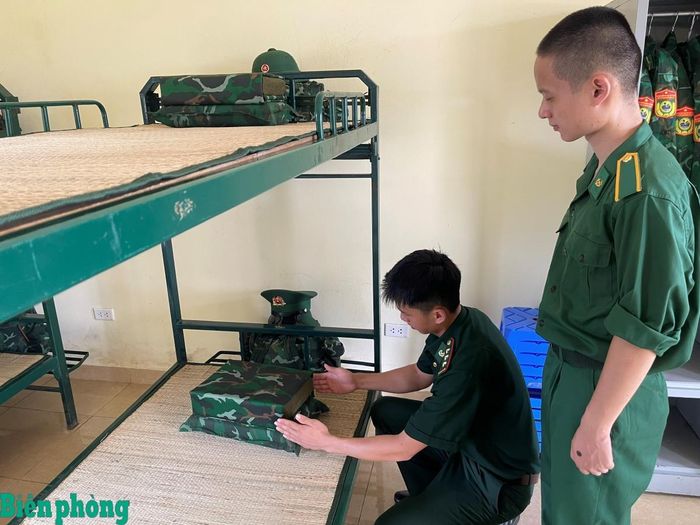 Cán bộ Học viện Biên phòng hướng dẫn học viên Nguyễn Thuận Thành gấp chăn màn, sắp xếp nội vụ trong những ngày đầu nhập học. Ảnh: Hợp Nguyễn