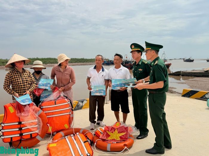 Cán bộ Bộ đội Biên phòng thành phố Hải Phòng tuyên truyền, phổ biến pháp luật, trao tặng cờ Tổ quốc, áo phao cho ngư dân. Ảnh: Nguyễn Khánh