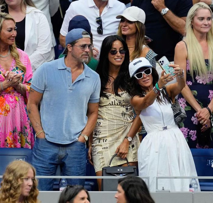 Brad Pitt chọn trang phục đơn giản khi đi xem quần vợt. Anh mặc áo polo xanh nhạt, phối quần jeans và đội ngược mũ lưỡi trai, phong độ ở tuổi 62. Ines de Ramon diện váy ngắn in họa tiết.