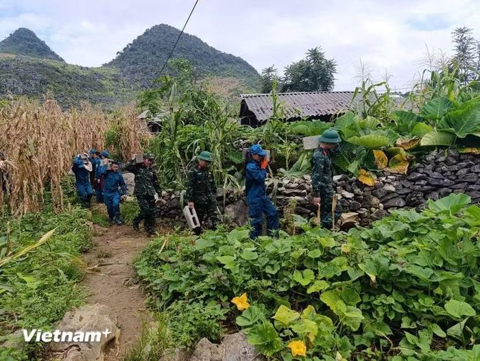 Lực lượng ở cơ sở hỗ trợ người dân vận chuyển vật liệu xây dựng nhà ở. (Ảnh Minh Tâm/Vietnam+)