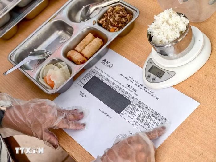 Đại diện cơ quan chuyên môn, nhà trường và phụ huynh kiểm tra, cân định lượng suất ăn bán trú. (Ảnh: Trung Nguyên/TTXVN)