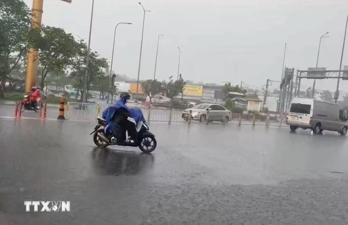 Người dân di chuyển trong cơn mưa trên đường Võ Văn Kiệt, phường An Lạc. (Ảnh: Hồng Đạt/TTXVN)