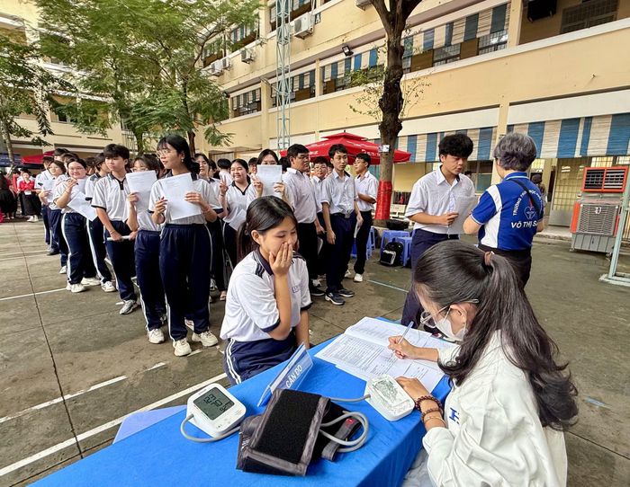 Các em học sinh xếp hàng chờ đo huyết áp.