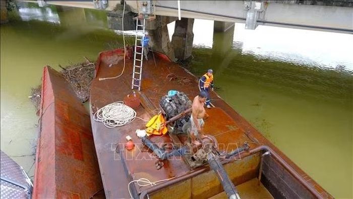 Lực lượng chức năng triển khai phương án xử lý hai xà lan mắc kẹt dưới chân cầu Mỹ Chánh. Ảnh: Thanh Thủy/TTXVN.