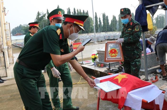 Lực lượng chức năng chụp ảnh lưu thông tin phần mộ để phục vụ đối chiếu, lập hồ sơ. Ảnh: Thanh Hòa - TTXVN