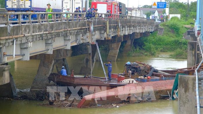 Hai xà lan bị mắc kẹt dưới chân cầu đường sắt Mỹ Chánh sau khi bị nước lũ cuốn trôi. Ảnh: Thanh Thuỷ-TTXVN