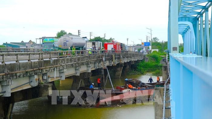 Lực lượng chức năng triển khai phương án xử lý hai xà lan mắc kẹt dưới chân cầu Mỹ Chánh. Ảnh: Thanh Thuỷ-TTXVN