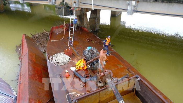Lực lượng chức năng triển khai phương án xử lý hai xà lan mắc kẹt dưới chân cầu Mỹ Chánh. Ảnh: Thanh Thuỷ-TTXVN