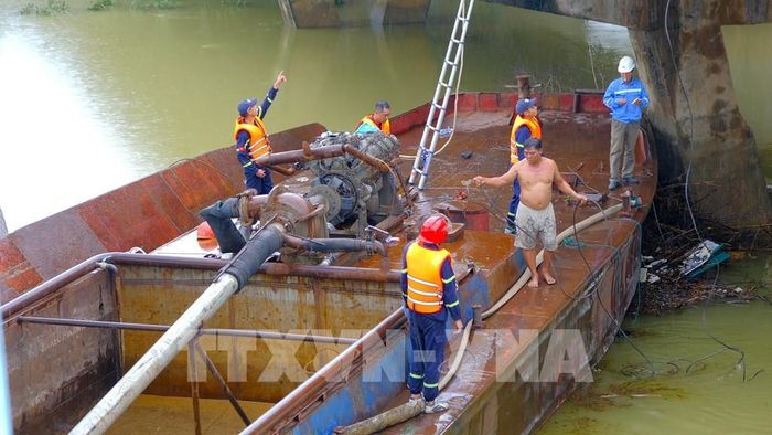 Lực lượng chức năng triển khai phương án xử lý hai xà lan mắc kẹt dưới chân cầu Mỹ Chánh. Ảnh: Thanh Thuỷ-TTXVN