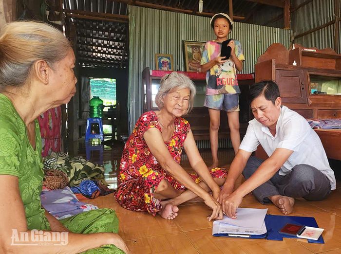 Công chức xã An Châu hỗ trợ người dân ấp Đông Bình Trạch thực hiện thủ tục ủy quyền nhận thay tiền bảo trợ xã hội tại nhà.
