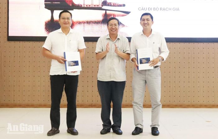 Phó Giám đốc Sở Xây dựng tỉnh An Giang Nguyễn Ngọc Lân (giữa) bàn giao quyết định và hồ sơ Quy hoạch chung đô thị Rạch Giá đến năm 2050 cho UBND phường Rạch Giá và Vĩnh Thông.