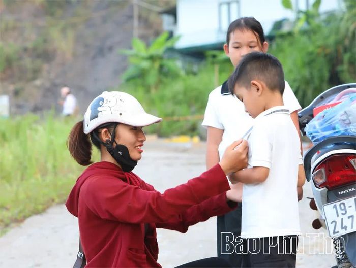 Các bậc phụ huynh chỉnh trang trang phục cho con em trước giờ tới lớp.