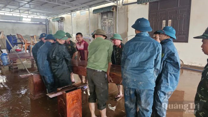 Cán bộ, chiến sĩ các lực lượng kê lại đồ đạc cho người dân sau khi nước lũ rút - Ảnh: P.K