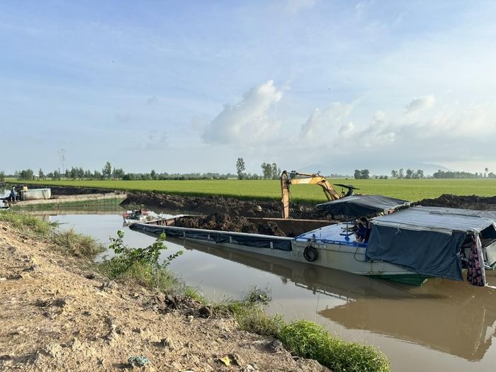 Máy đào đang múc đất sét dưới lòng kênh đưa lên xà lan để vận chuyển đi tiêu thụ. Ảnh: Công an tỉnh An Giang