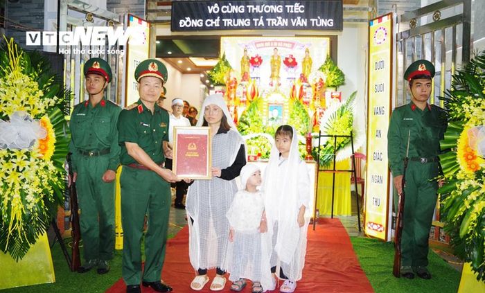 Thay mặt lãnh đạo Bộ Quốc phòng, Trung tướng Lương Văn Kiểm, Tư lệnh Quân khu 3 trao quyết định truy thăng quân hàm từ Thiếu tá lên Trung tá cho người sĩ quan trẻ Trần Văn Tùng. (Ảnh: Khánh Linh)