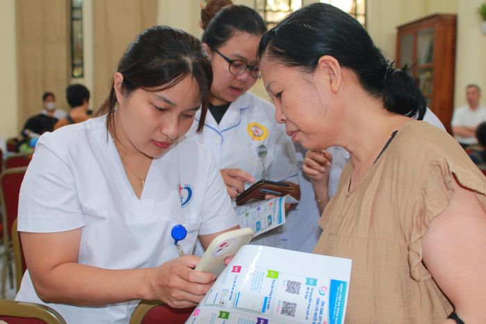 Nhân viên y tế hướng dẫn người dân cách tạo lập, tra cứu thông tin hồ sơ sức khoẻ. Ảnh: PV