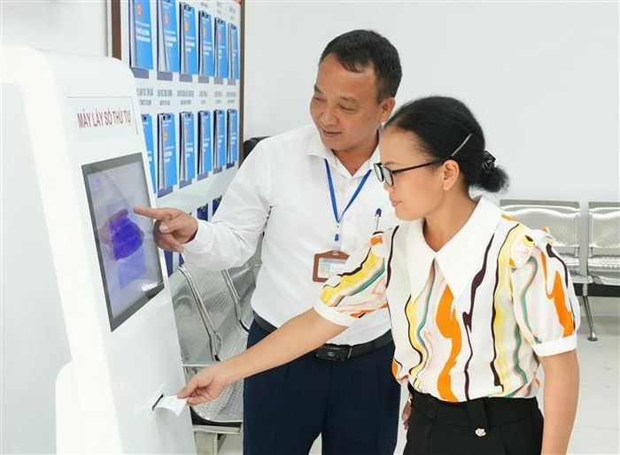 Cán bộ hướng dẫn người dân sử dụng máy lấy số thứ tự tại Trung tâm Phục vụ hành chính công tại Bắc Ninh. Ảnh: Đồng Thúy - TTXVN
