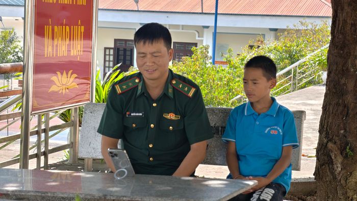  Trung tá Nguyễn Xuân Hưng, Chính trị viên Đồn Biên phòng Lũng Cú cùng con nuôi Giàng Mí Nhù trò chuyện trực tuyến với Thò Thị Dính. Ảnh: Huy Thông 