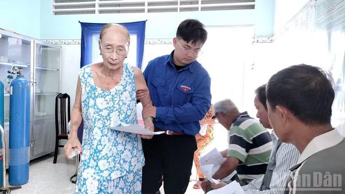 Bà Trương Kim Tuyết (77 tuổi, ngụ xã Hòa Bình) được cán bộ đoàn hỗ trợ vào khu khám sàng lọc. (Ảnh HỮU TÙNG)