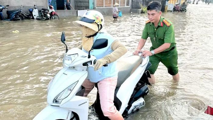 Lực lượng Công an phường hỗ trợ người dân di chuyển qua khu vực ngập sâu. (Ảnh: Công an cung cấp)