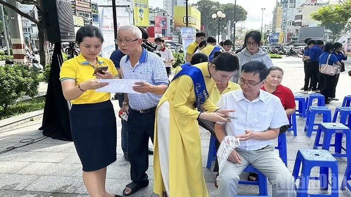 Thanh niên tình nguyện và học sinh hỗ trợ người dân phường Chợ Quán tiếp cận và sử dụng các ứng dụng, tiện ích số thiết yếu. (Ảnh: HOÀNG LIÊM)