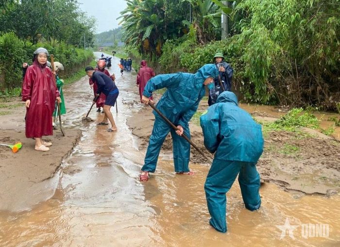 Dân quân và bà con nhân dân khơi thông bùn đất tại tuyến đường. 