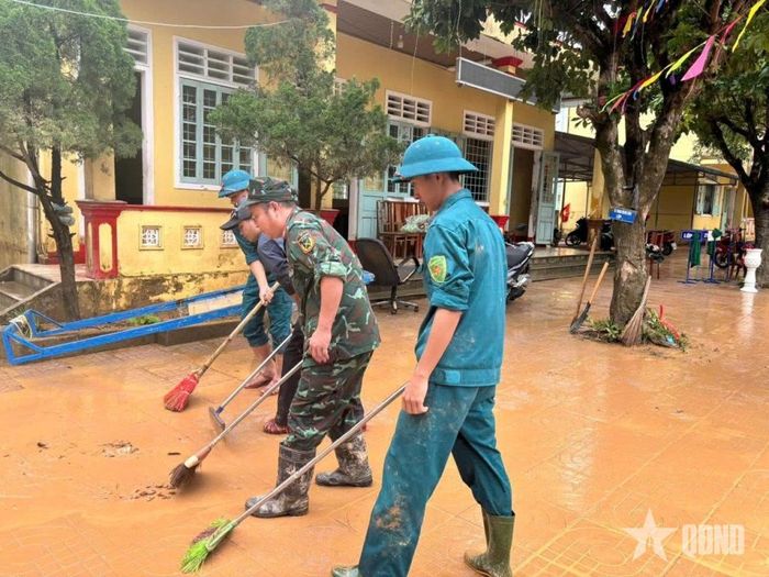 Bộ đội, dân quân giúp các trường học dọn dẹp sau lũ. 