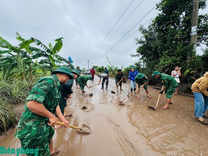 Cán bộ, chiến sĩ Bộ đội Biên phòng tỉnh Quảng Trị phối hợp với chính quyền địa phương và nhân dân dọn dẹp bùn đất trên các tuyến đường sau mưa lớn, góp phần sớm khôi phục giao thông. Ảnh: Đình Tiến