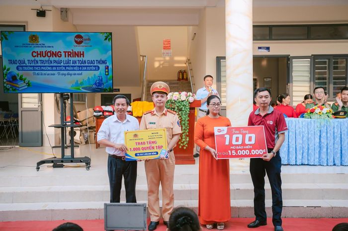 Đại diện đơn vị tài trợ trao biểu trưng 1.000 quyển tập và 150 mũ bảo hiểm cho Ban Giám hiệu Trường THCS phường An Xuyên, Phân hiệu 4. Ảnh: H.Đ.