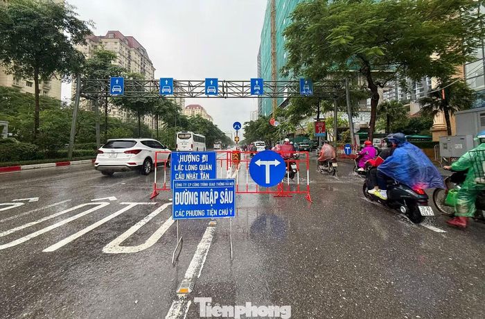 Lực lượng chức năng đặt biển cảnh báo tại khu vực ngập sâu và hướng dẫn phương tiện di chuyển an toàn.