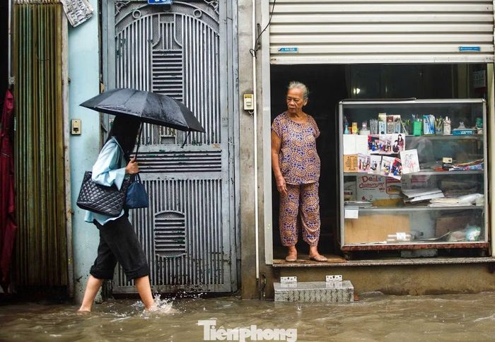 Nước ngập trên phố Triều Khúc khiến một số người xuống xe, đi bộ qua đoạn nước sâu.