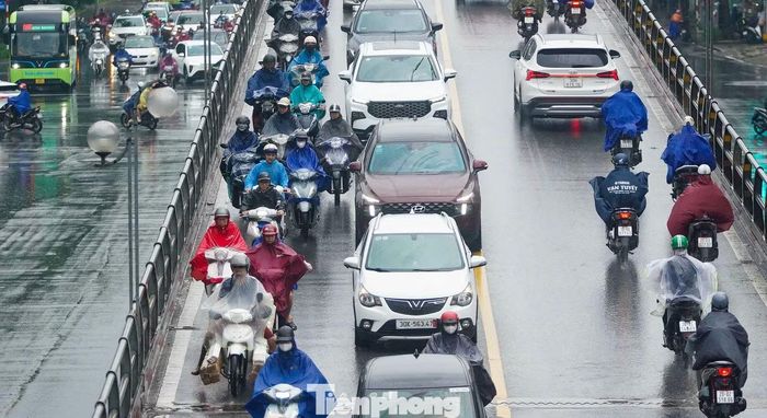 Trên cầu vượt Thái Hà, các phương tiện nối đuôi nhau, di chuyển chậm trong mưa.
