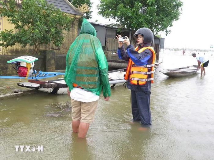 Phóng viên Mai Trang, CQTT Thông tấn xã Việt Nam tại Huế tác nghiệp tại rốn lũ phường Hóa Châu, thành phố Huế. (Ảnh: TTXVN)
