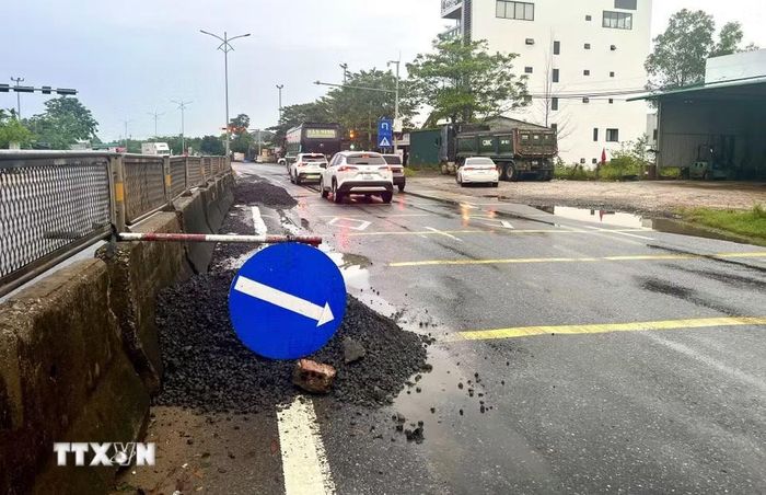 Lực lượng chức năng cắm biển cảnh báo, hướng dẫn phương tiện lưu thông qua đoạn Quốc lộ 1A bị hư hỏng tại xã Hải Lăng (Quảng Trị). (Ảnh: Nguyên Linh/TTXVN)