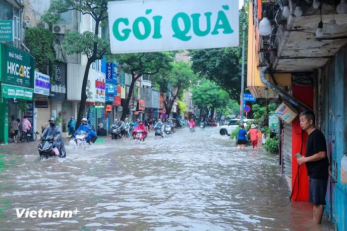Mưa lớn kéo dài từ đêm qua khiến một số tuyến đường của Hà Nội ngập sâu, người dân chật vật đưa con đi học đi làm. (Ảnh: Hoài Nam/Vietnam+)