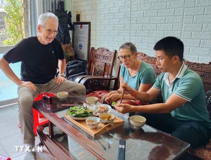 Du khách quốc tế hào hứng nếm thử các món ẩm thực địa phương chấm nước mắm khi tham quan làng cổ Nam Ô, phường Hải Vân, thành phố Đà Nẵng. (Ảnh: Quốc Dũng/TTXVN)