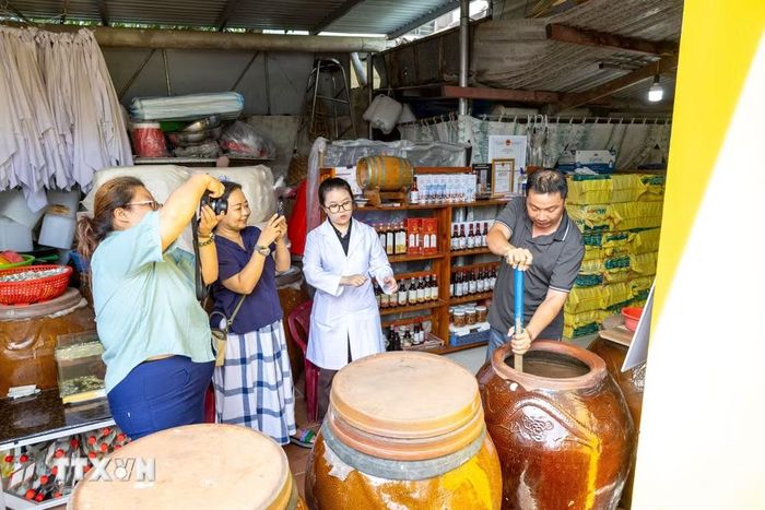 Du khách tìm hiểu quy trình ủ chượp nước mắm tại làng Nam Ô, phường Hải Vân, thành phố Đà Nẵng. (Ảnh: Xuân Quý/TTXVN)