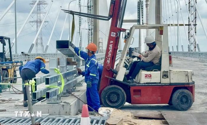 Máy móc, người lao động lắp đặt lan can trên cầu Phước Khánh (cao tốc Bến Lức-Long Thành). (Ảnh: Công Phong/TTXVN)