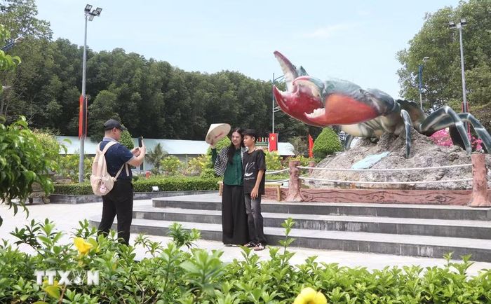 Khách du lịch chụp ảnh tại biểu tượng con cua tại Khu du lịch Mũi Cà Mau. (Ảnh: Tuấn Phi/TTXVN)
