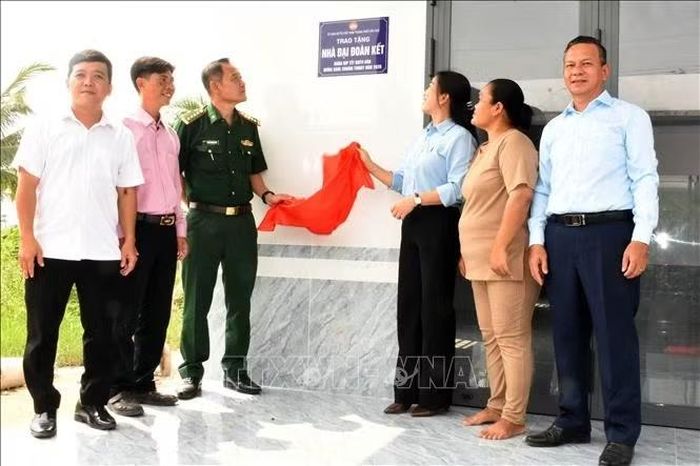 Các đại biểu cùng gia đình thực hiện nghi thức mở băng khánh thành công trình nhà Đại đoàn kết tại khu vực Bưng Tum, phường Khánh Hòa.