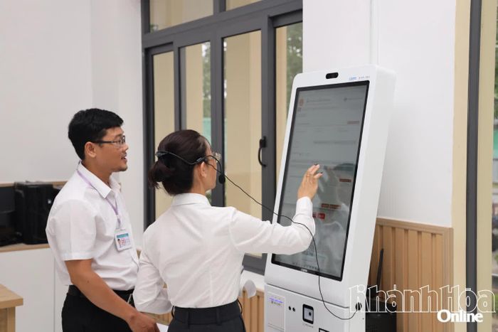 Lãnh đạo Trung tâm Phục vụ hành chính công phường Cam Ranh hướng dẫn người dân sử dụng robot AI để nộp hồ sơ trực tuyến. Ảnh: VĂN KỲ
