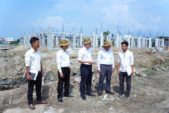 Lãnh đạo Đảng ủy xã nghe nhà thầu thi công báo cáo tiến độ công trình chợ trung tâm.