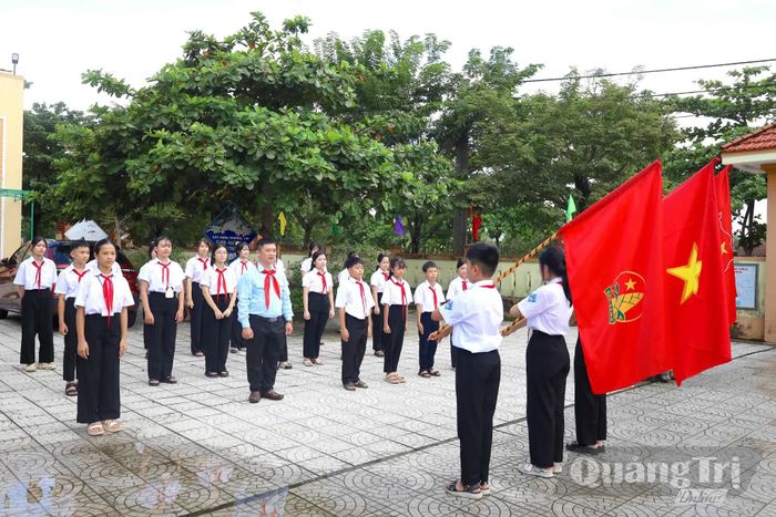 Thầy giáo Hồ Văn Hợi hướng dẫn đội viên luyện tập nghi thức Đội tại sân trường - Ảnh: Q.N