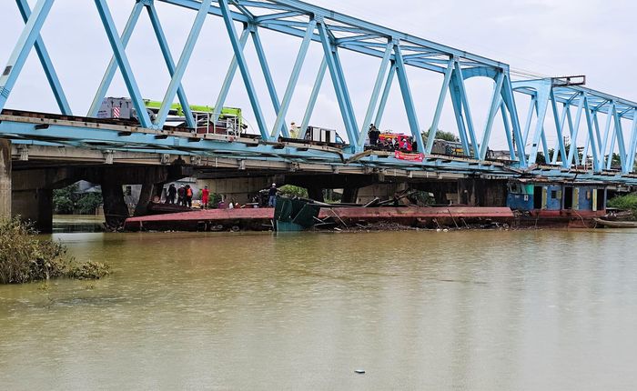Đây là chiếc sà lan còn nổi, mũi sà lan kê vào trụ cầu đường bộ, bị mắc kẹt một phía là trụ cầu đường bộ và trụ cầu đường sắt, phía còn lại là chiếc sà lan bị lật nghiêng.