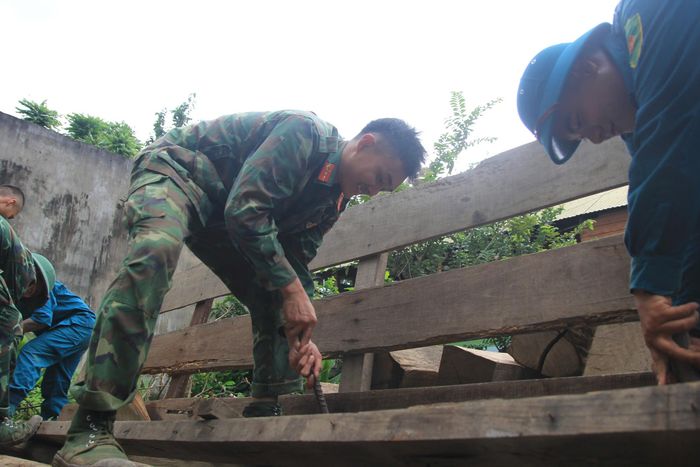 Chiến sĩ trẻ tháo đinh cũ trong căn nhà cũ của người dân. 
