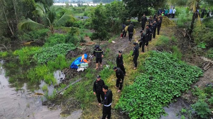 Các chiến sĩ Trung đoàn Cảnh sát cơ động số 9 đưa những cây lúa đã cắt lên trên bờ.