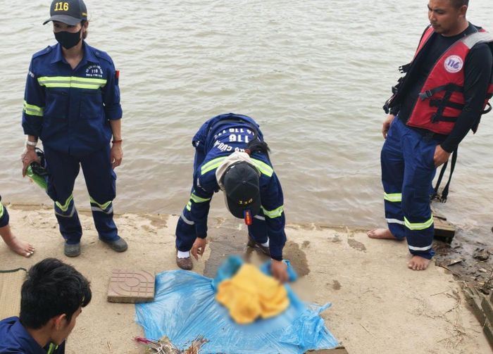Thi thể bé trai sơ sinh được đưa lên bờ. (Ảnh: Nhâm Quang Văn)