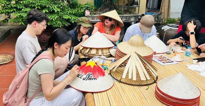 Du khách trải nghiệm làm nón lá Tri Lễ tại xã Dân Hòa. Ảnh: TRILAF.