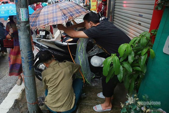 Người dân tranh thủ sửa xe máy gặp sự cố ngay bên đường. Ảnh: T.Anh